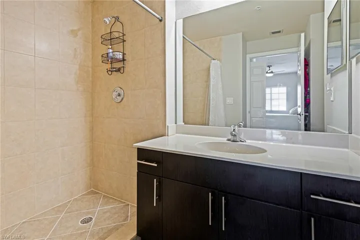 Bathroom with walk in shower, vanity, and ceiling fan