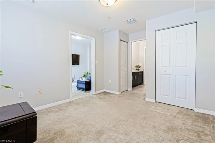Unfurnished bedroom with connected bathroom and light colored carpet