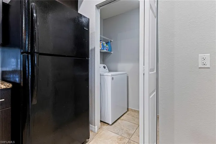 Washroom with light tile flooring and washer / dryer