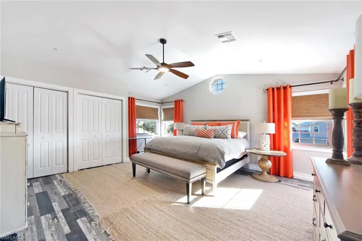 Bedroom featuring light wood-style floors, multiple closets, vaulted ceiling, and a ceiling fan