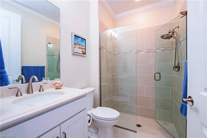 Glass-enclosed shower with a rainfall showerhead, tile surround, and mosaic accent band