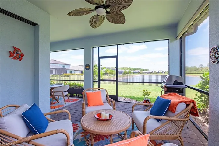 Screened patio featuring paver flooring, a ceiling fan with integrated lighting, and a serene water backdrop