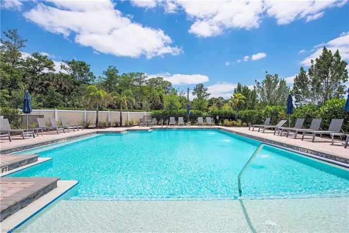 Resort-style pool area featuring ample lounging space, integrated steps, and surrounding mature landscaping