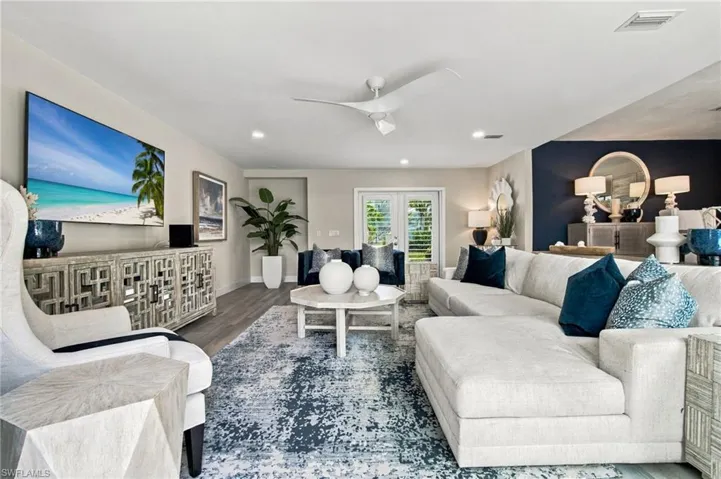 Recessed lighting, wood-finish flooring, ceiling fan with integrated lighting, dual French doors, and accent wall