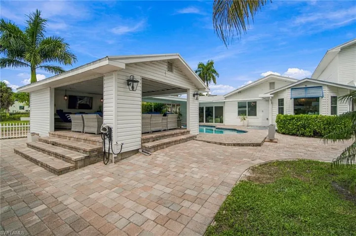 Outdoor living area with a covered patio, swimming pool, and paver hardscaping
