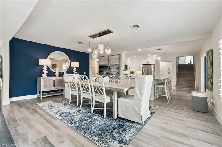 Open-concept living area featuring wood-finish flooring, recessed lighting, and a modern linear pendant light fixture