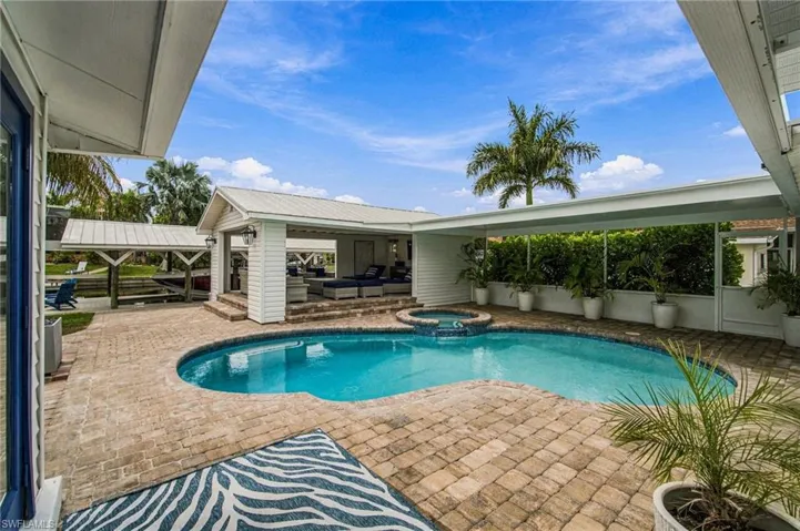 Pool deck with pavers, built-in spa, covered patio, and attached boathouse