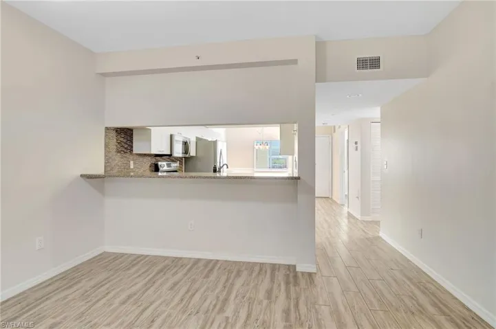 Kitchen with appliances with stainless steel finishes, light wood finished floors, white cabinetry, baseboards, and a peninsula