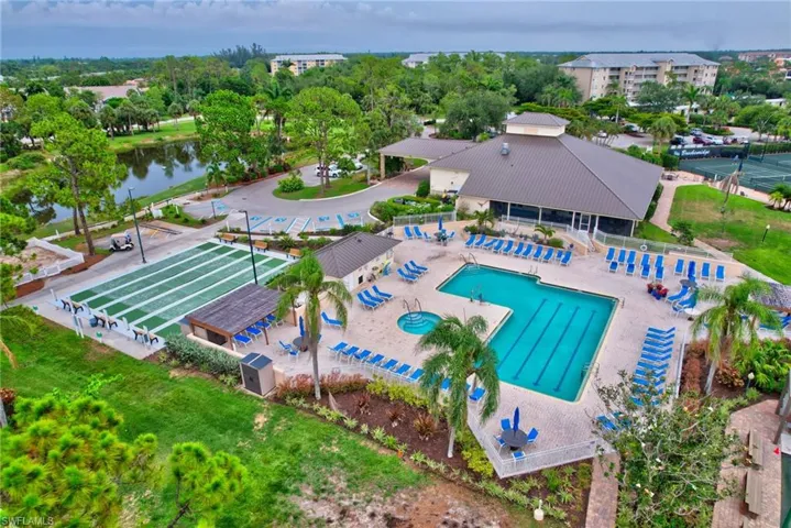 Drone / aerial view of a pool area, a large body of water, and a tree filled landscape