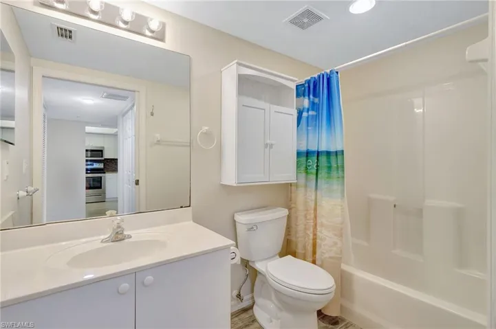 Full bath featuring toilet, vanity, shower / tub combo, and baseboards