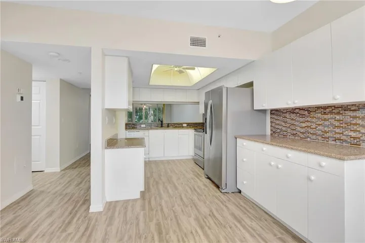 Kitchen featuring light wood finished floors, a ceiling fan, stove, and stainless steel fridge