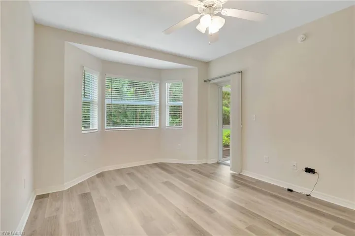 Spare room with light wood finished floors, baseboards, a ceiling fan, and a smoke detector