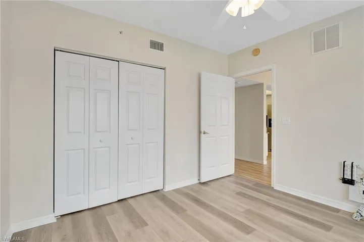 Unfurnished bedroom with light wood-style flooring, a closet, baseboards, and ceiling fan