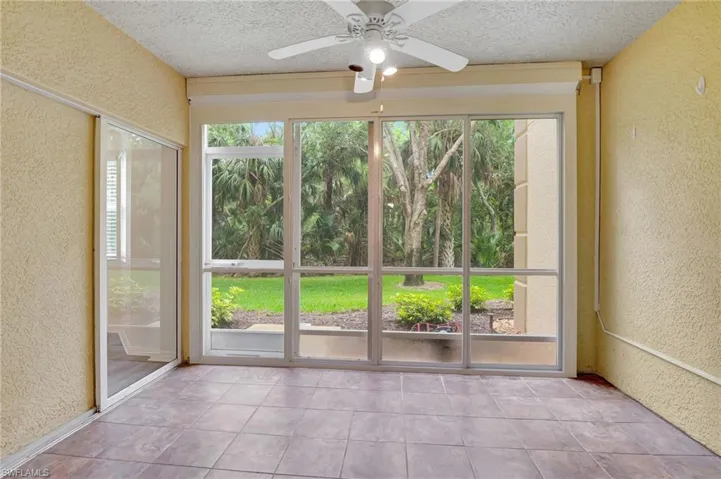 Unfurnished sunroom featuring a textured wall, a textured ceiling, and tile patterned floors