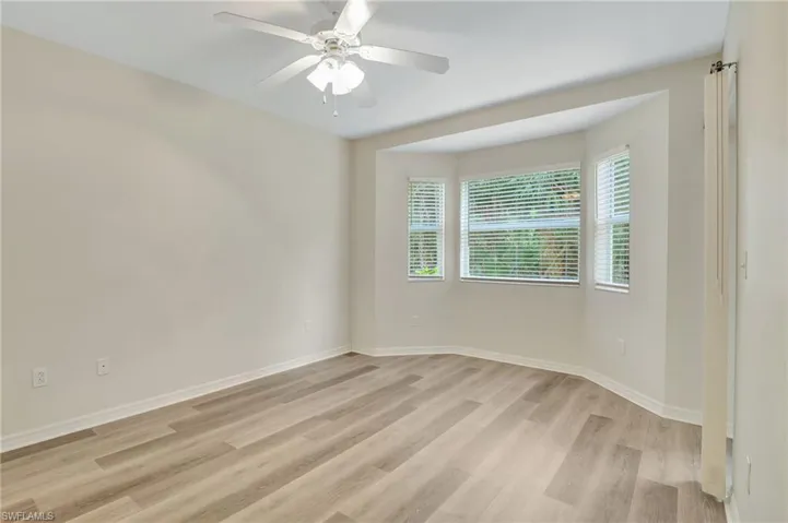 Unfurnished room with light wood finished floors, ceiling fan, and baseboards