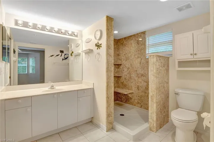 Bathroom featuring vanity, tile patterned floors, a walk in shower, and plenty of natural light