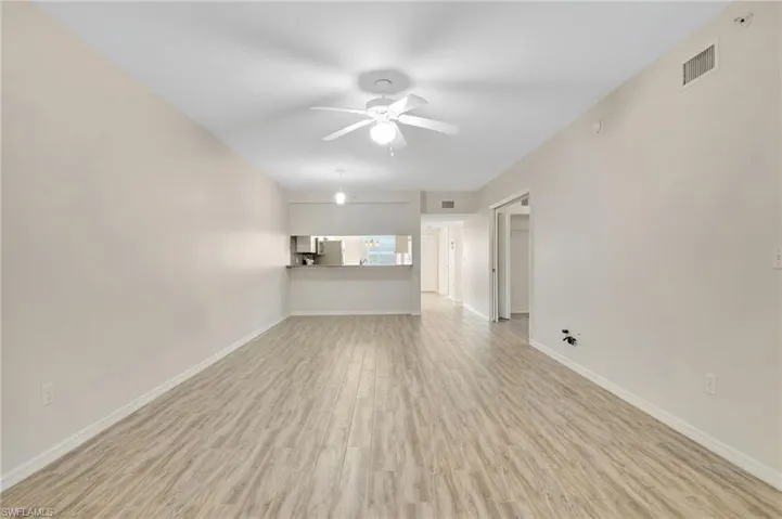 Unfurnished living room with a ceiling fan, light wood-style floors, and baseboards