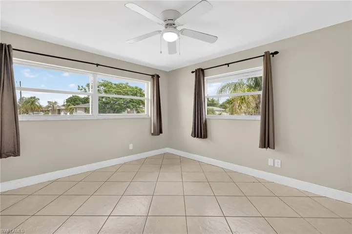 Spare room featuring plenty of natural light, ceiling fan, and light tile patterned flooring
