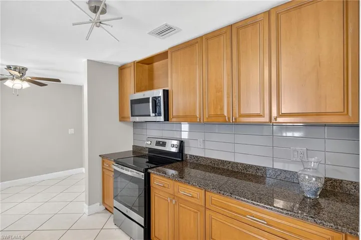 Kitchen with appliances with stainless steel finishes, a ceiling fan, light tile patterned flooring, and backsplash