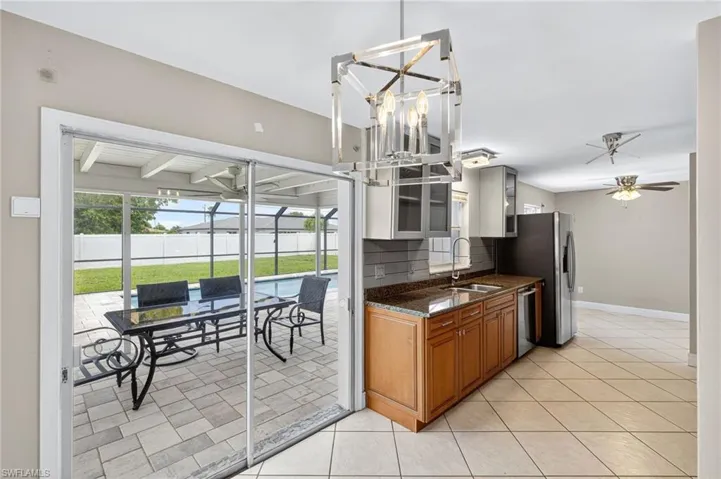 Kitchen with stainless steel appliances, brown cabinets, tasteful backsplash, light tile patterned flooring, and ceiling fan