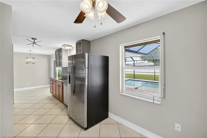 Kitchen featuring stainless steel fridge, light tile patterned floors, glass insert cabinets, and plenty of natural light