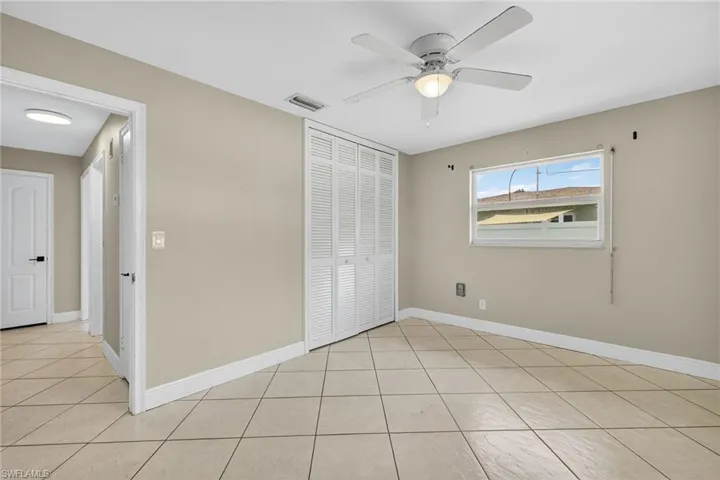 Unfurnished bedroom featuring a closet, light tile patterned floors, and a ceiling fan