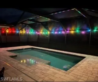 Pool at night with an outdoor pool and a patio