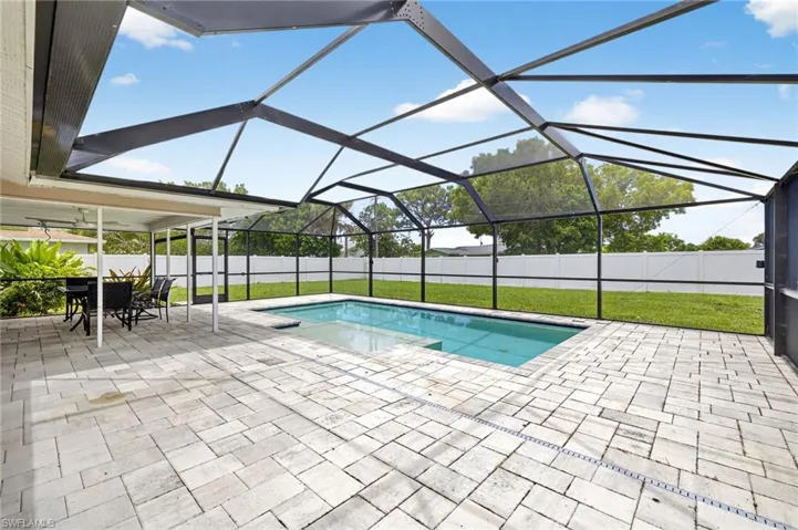 View of pool with a patio area, a fenced backyard, and glass enclosure