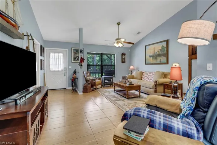 Living room with lofted ceiling, ceiling fan, and light tile patterned flooring