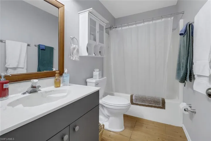 Full bathroom featuring shower / bathtub combination with curtain, tile patterned floors, vanity, and toilet