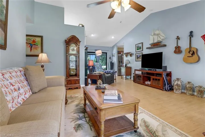 Living room with high vaulted ceiling, light wood-type flooring, and ceiling fan