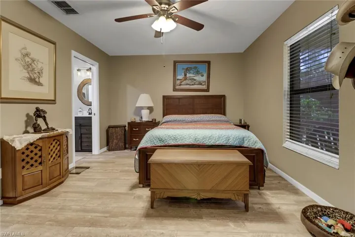 Bedroom featuring multiple windows, ceiling fan, ensuite bathroom, and light hardwood / wood-style flooring