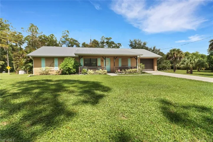 Ranch-style home featuring a front yard, a garage, and covered porch
