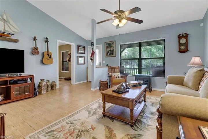 Living room featuring light hardwood / wood-style flooring, vaulted ceiling, and ceiling fan