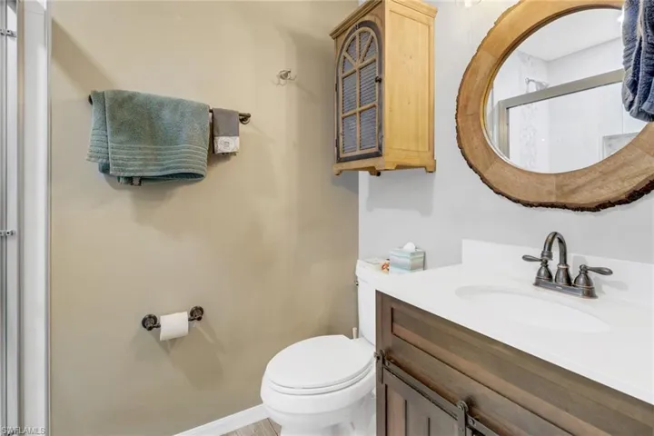 Bathroom featuring a shower with door, vanity, and toilet