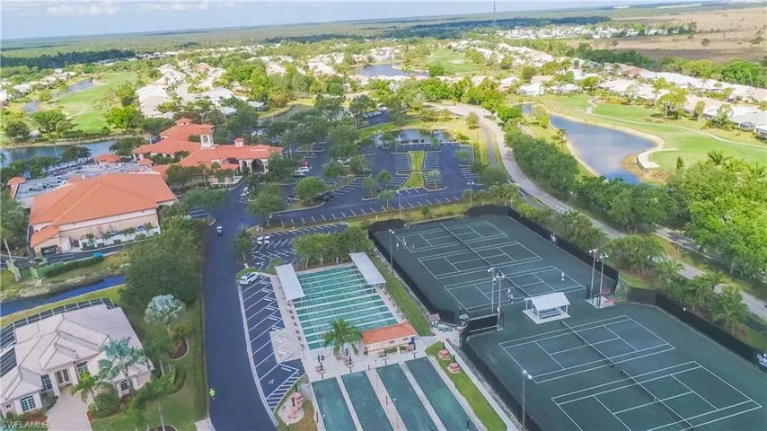 Expansive property featuring multiple tennis courts, bocce ball courts, a clubhouse with a terracotta tile roof, and a golf course with water features