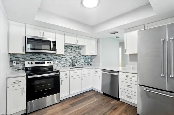 Kitchen featuring appliances with stainless steel finishes, white cabinetry, and a tray ceiling