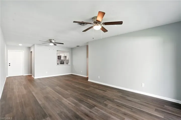 Unfurnished living room featuring ceiling fan and dark wood finished floors