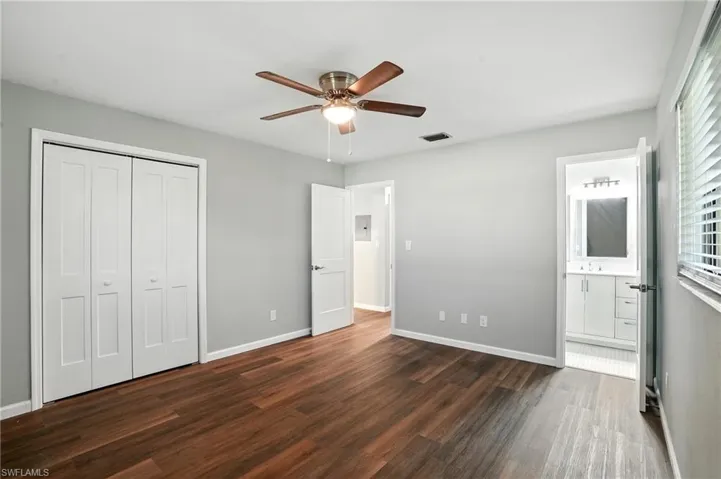 Unfurnished bedroom with dark wood-style flooring, ceiling fan, a closet, and connected bathroom
