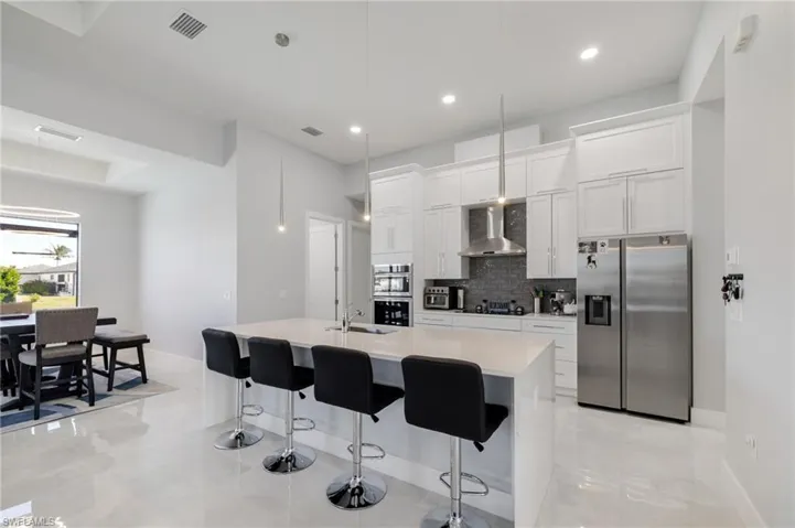 Kitchen with appliances with stainless steel finishes, a breakfast bar area, hanging light fixtures, a kitchen island with sink, and recessed lighting