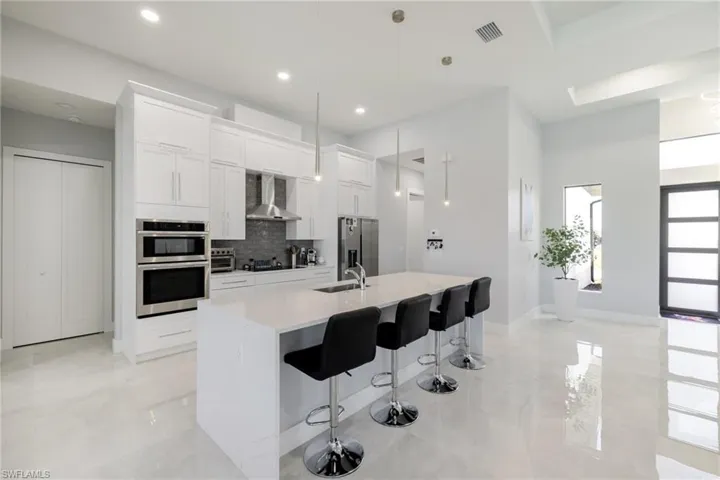 Kitchen featuring a breakfast bar, white cabinets, stainless steel appliances, and pendant lighting