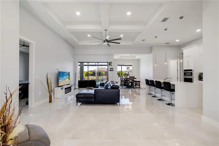 Living room with coffered ceiling, beamed ceiling, a ceiling fan, a high ceiling, and recessed lighting