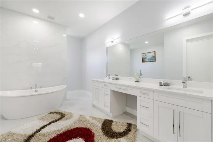 Bathroom with a freestanding tub, double vanity, and recessed lighting