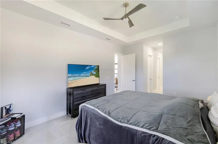 Bedroom featuring a tray ceiling, a ceiling fan, recessed lighting, and light tile patterned flooring