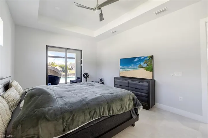 Bedroom with access to exterior, a tray ceiling, and a ceiling fan