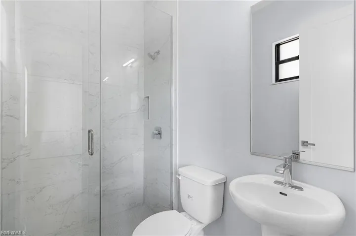 Full bathroom featuring toilet and a marble finish shower