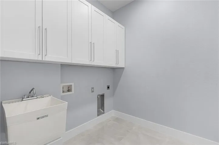 Washroom featuring electric dryer hookup, hookup for a washing machine, and cabinet space