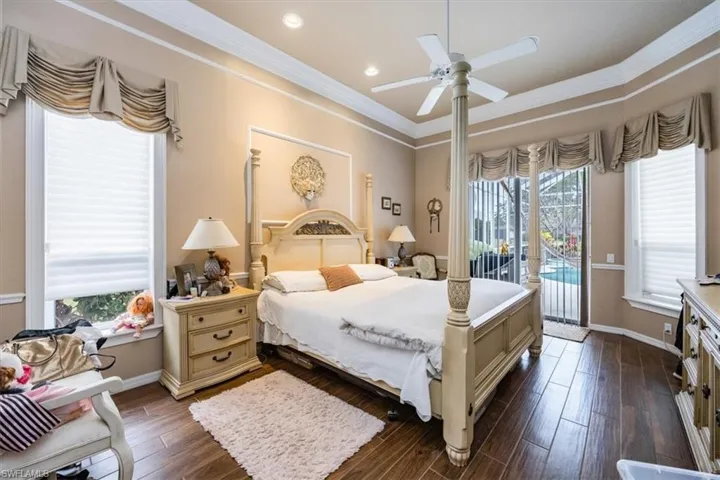 Bedroom with dark wood-type flooring, multiple windows, access to outside, crown molding, and recessed lighting