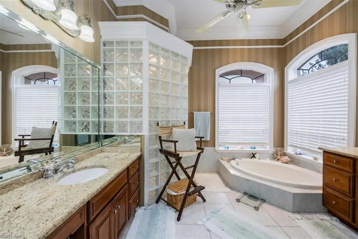 Full bathroom featuring vanity, a bath, light tile patterned floors, ornamental molding, and ceiling fan