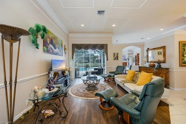 Living room featuring arched walkways, hardwood / wood-style flooring, ornamental molding, and recessed lighting